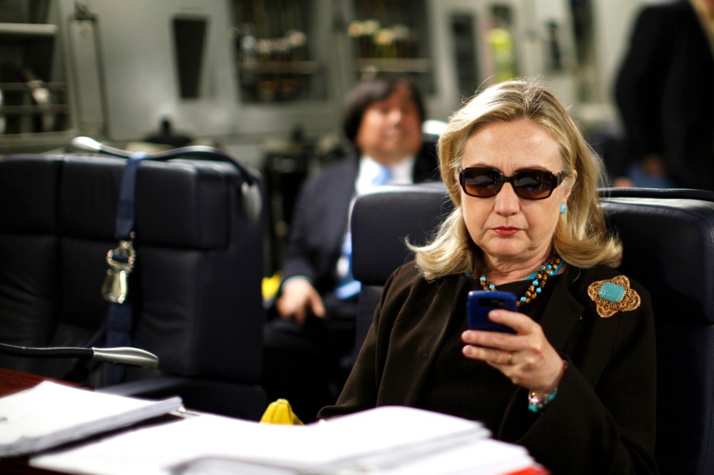 Secretary of State Hillary Clinton checks her phone upon her departure in a military plane from Malta bound for Tripoli, Libya on Oct. 18, 2011. (Photo by Kevin Lamarque/Reuters)
