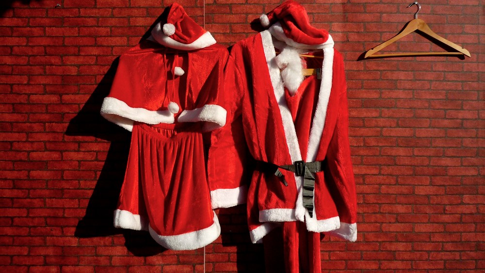 Santa Claus costumes, for a man and woman, hang on the front of a Christmas decorations stall at a market. (Photo by David Gray/Reuters)