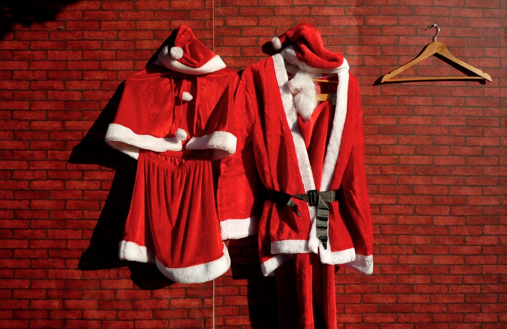 Santa Claus costumes, for a man and woman, hang on the front of a Christmas decorations stall at a market. (Photo by David Gray/Reuters)