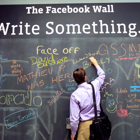 An employee writes a note on the message board at the new headquarters of Facebook in Menlo Park, Calif., Jan. 11, 2012. (Photo by Robert Galbraith/Reuters)