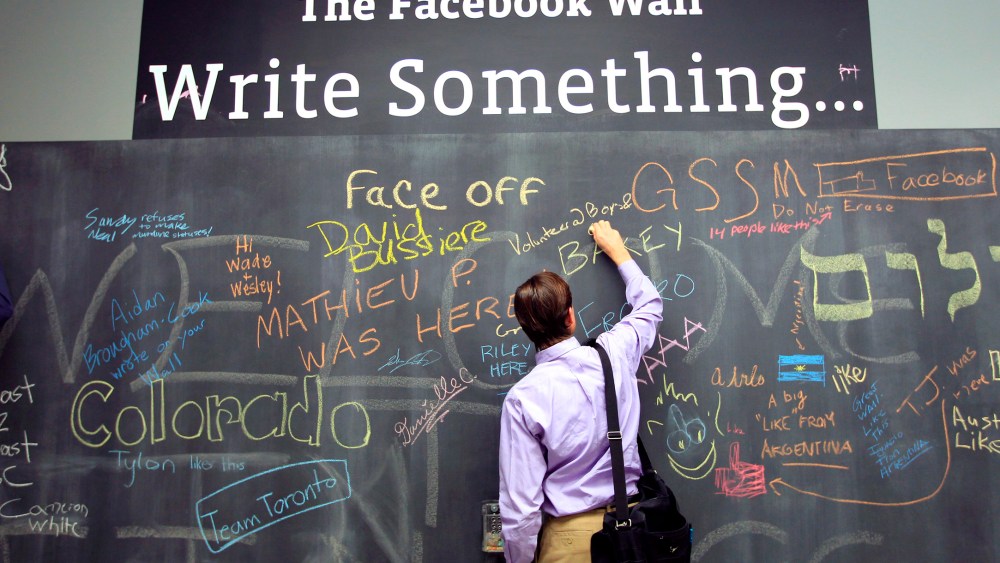 An employee writes a note on the message board at the new headquarters of Facebook in Menlo Park, Calif., Jan. 11, 2012. (Photo by Robert Galbraith/Reuters)