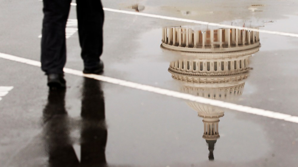 The dome of the U.S. Capitol Building is reflected in a puddle on a rainy morning in Washington.