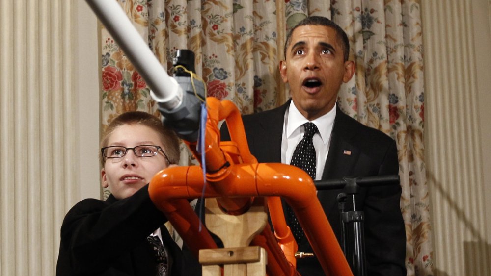 President Barack Obama reacts as Joey Hudy of Phoenix, Arizona, launches a marshmallow from his Extreme Marshmallow Cannon in the State Dining Room of the White House during the second White House Science Fair in Washington February 7, 2012.