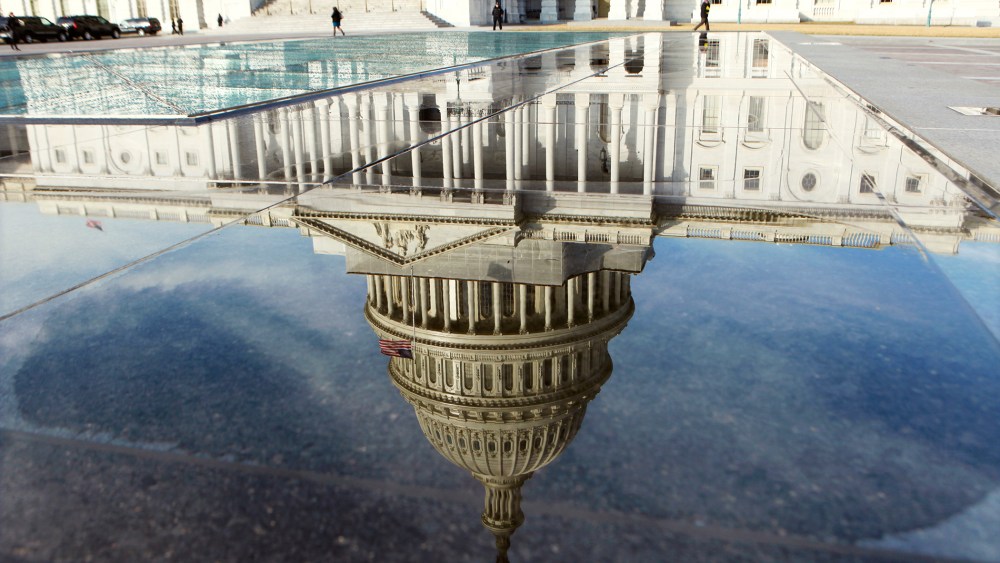 The dome of the Capitol is reflected in a puddle in Washington, Feb. 17, 2012.