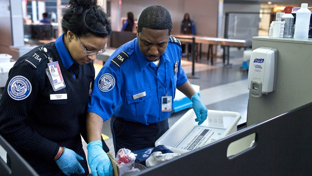 Two TSA security agents check a traveler's luggage at John F. Kennedy Airport in New York