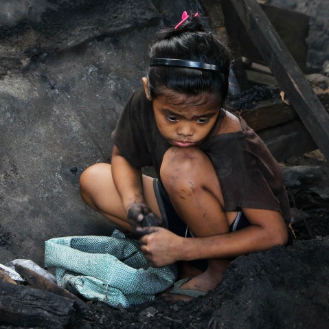 A girl collects pieces of charcoal for sale at a market, in Manila, the Philippines, March 2, 2012. (Photo by Romeo Ranoco/Reuters)