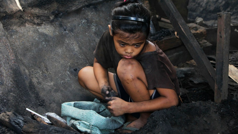 A girl collects pieces of charcoal for sale at a market, in Manila, the Philippines, March 2, 2012. (Photo by Romeo Ranoco/Reuters)