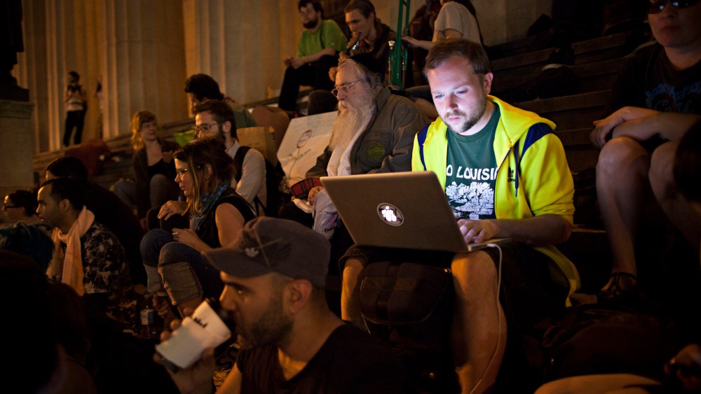 An Occupy Wall Street protester works on a laptop on the steps of Federal Hall