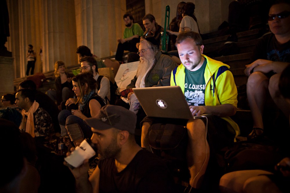 An Occupy Wall Street protester works on a laptop on the steps of Federal Hall