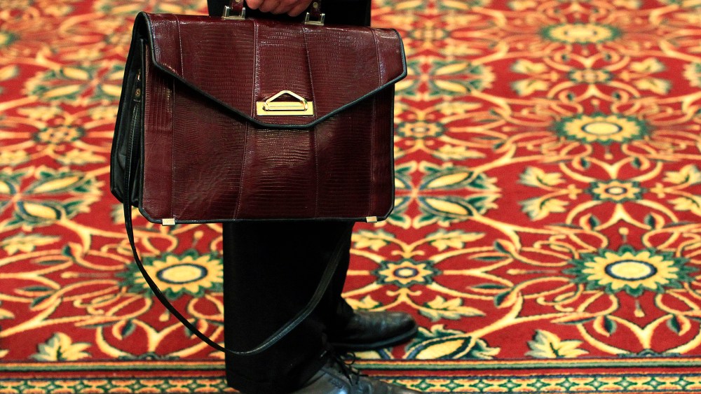 A man holds his briefcase while waiting in line during a job fair in Melville, New York July 19, 2012.