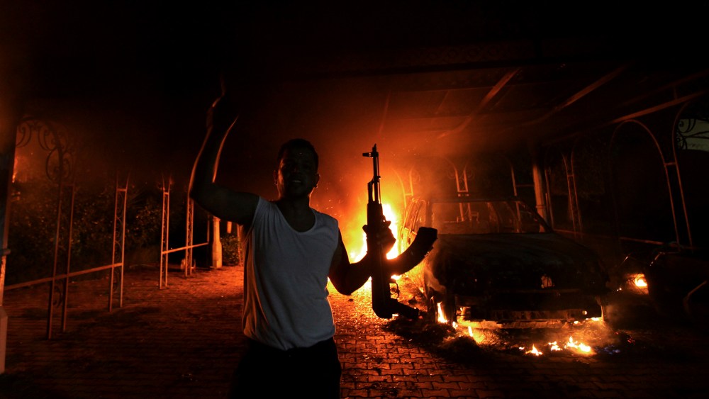 A protester reacts as the U.S. Consulate in Benghazi is seen in flames