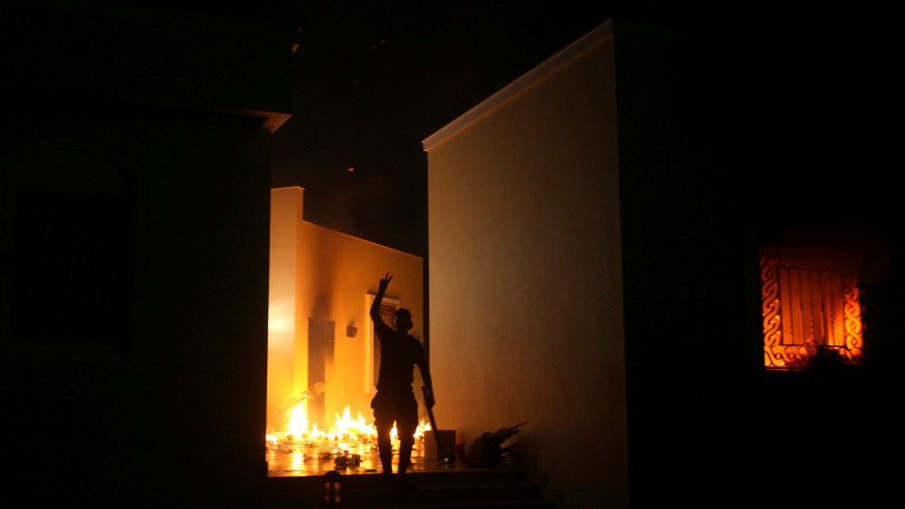 A protester reacts as the U.S. Consulate in Benghazi is seen in flames