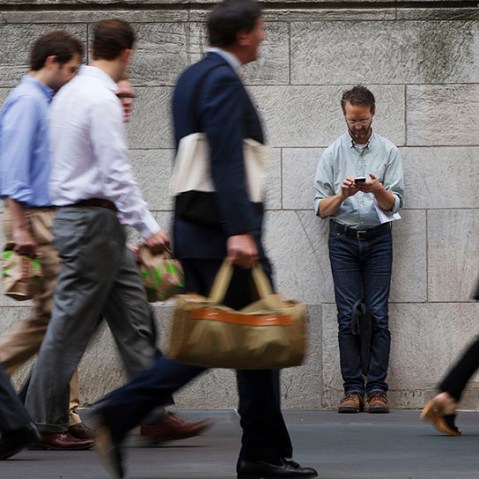 A man stops to lean against a building as pedestrians walk past while he looks down at his cell phone on 5th Avenue in New York, NY. (Photo by Lucas Jackson/Reuters)
