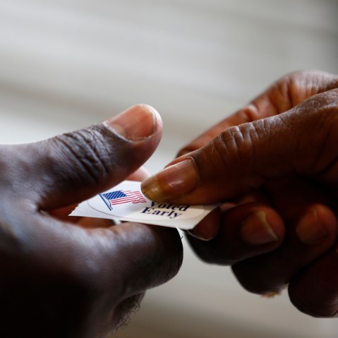 A poll worker hands a sticker to a voter at a polling place in Charlotte, North Carolina October 27, 2012. (Photo by Chris Keane/Reuters)