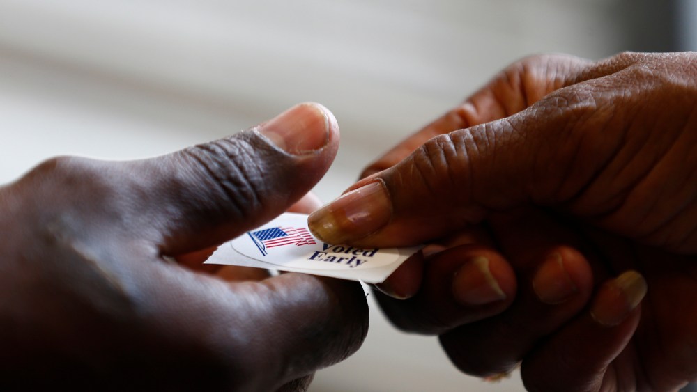 A poll worker hands a sticker to a voter at a polling place in Charlotte, NY.