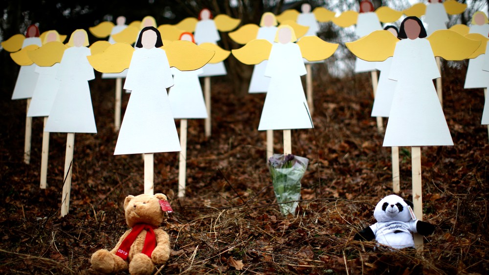 Stuffed animals left by mourners sit beneath some of the 27 wooden angel figures beside a road near the Sandy Hook Elementary School for the victims of a school shooting in Newtown, Connecticut Sunday Dec. 16, 2012.