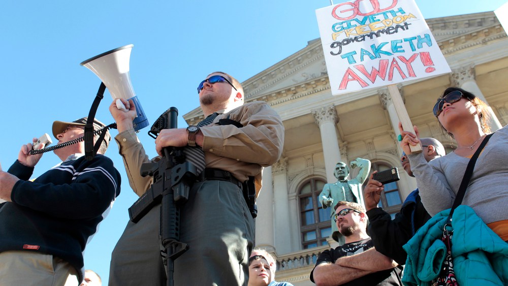 Michael Rugh (2nd-L) holds a AR-15 rifle as he participates along with David Mace (L) and Luchie Wooten (R), during the Guns Across America pro-gun rally at the State Capitol in Atlanta, Georgia, Jan. 19, 2013