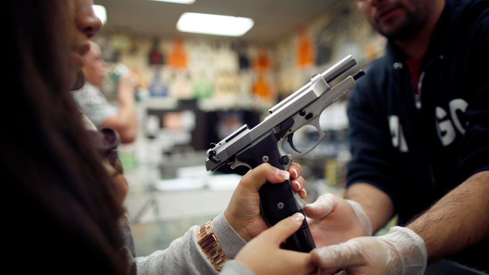 Range safety officer Luis Pena, 23, (R) demonstrates gun safety to Faith Herradura, 23, at the Los Angeles gun club in Los Angeles, on January 23, 2013.