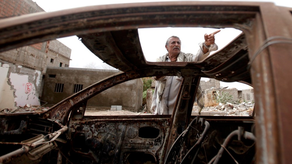 Muhammad Saleh Abdullah, 65, a resident of the southern Yemeni town of Jaar, gestures as he stands near his car destroyed by an air strike last year that was targeting al Qaeda-linked militants, in Jaar February 1, 2013