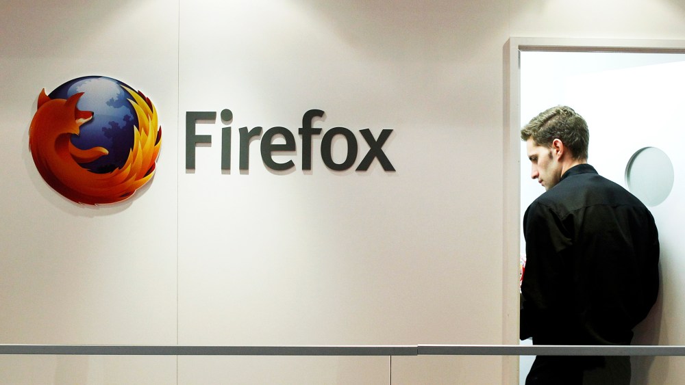 A man is seen next to a Firefox logo at a Mozilla stand during the Mobile World Congress in Barcelona, Feb. 28, 2013.