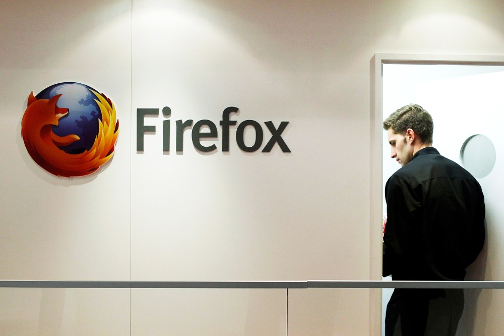 A man is seen next to a Firefox logo at a Mozilla stand during the Mobile World Congress in Barcelona, Feb. 28, 2013.