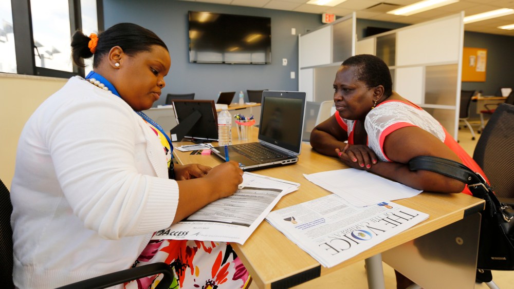 Certified Application Counselor Sheslie Caze (L) takes information from a woman as she inquired about the Affordable Care Act insurance at the Borinquen Medical Center in Miami on Oct. 1, 2013.