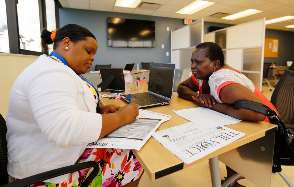 Certified Application Counselor Sheslie Caze (L) takes information from a woman as she inquired about the Affordable Care Act insurance at the Borinquen Medical Center in Miami on Oct. 1, 2013.