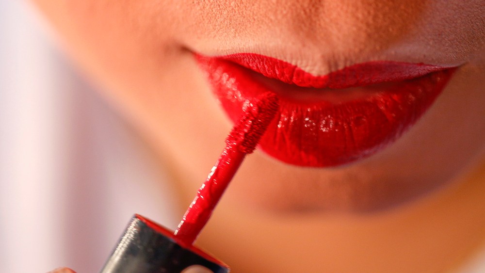 A woman applies applies red lipstick. (Photo by Athit Perawongmetha/Reuters)