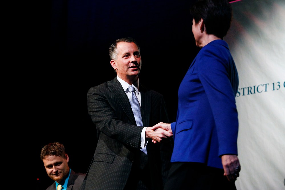 Democrat Alex Sink (C) and Republican David Jolly, both candidates for Florida's congressional District 13, shake hands before participating in a candidate forum in Clearwater, Florida, February 25, 2014.