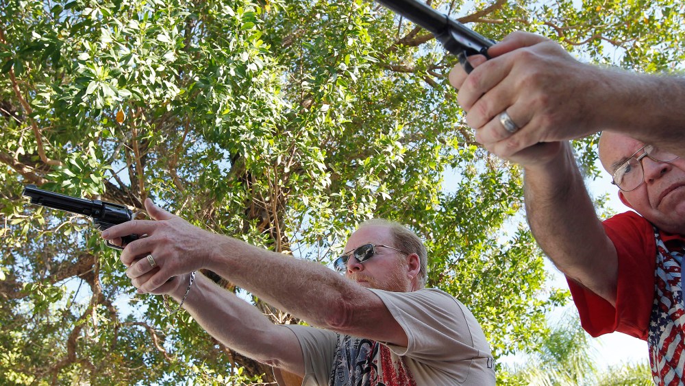 Varrieur and Gordon practice their firing stance with unloaded weapons in the yard of Varrieur's home in Big Pine Keys. (Photo by Andrew Innerarity/Reuters)