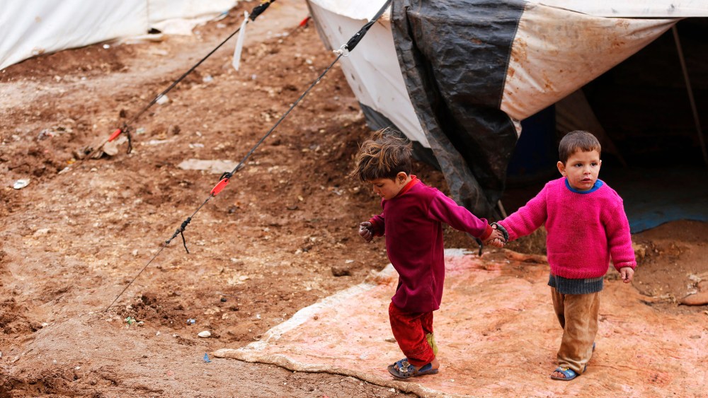 Syrian refugee children walk through mud at the Bab Al-Salam refugee camp in Azaz, near the Syrian-Turkish border, March 14, 2014.