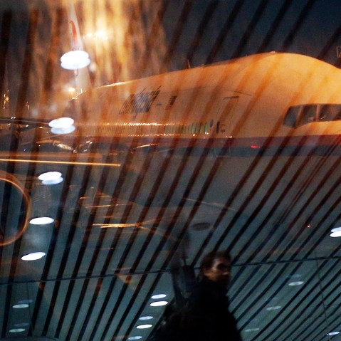 Malaysia Airlines Boeing 777-200ER flight MH318 to Beijing sits on the tarmac as passengers are reflected in the glass at the boarding gate at Kuala Lumpur International Airport, March 17, 2014.
