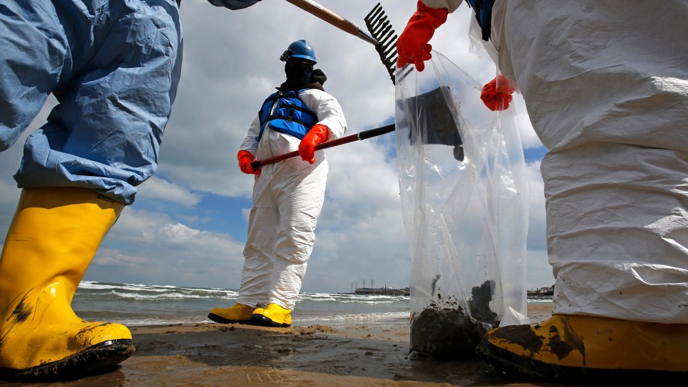 Oil spill response contractors clean up crude oil on a beach after a BP oil spill on Lake Michigan, March 25, 2014, in Whiting, Indiana.