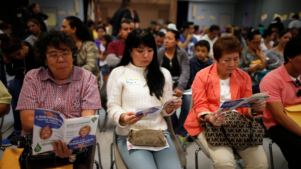 People wait in line at a health insurance enrollment event, March 27, 2014 in Cudahy, Calif.