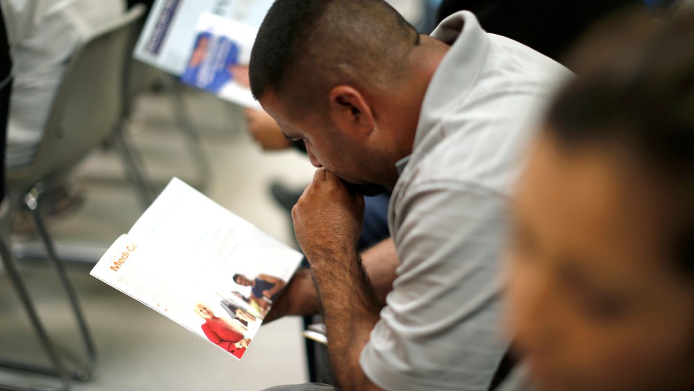 People read pamphlets as they wait in line at a health insurance enrollment event in Cudahy, California on March 27, 2014.