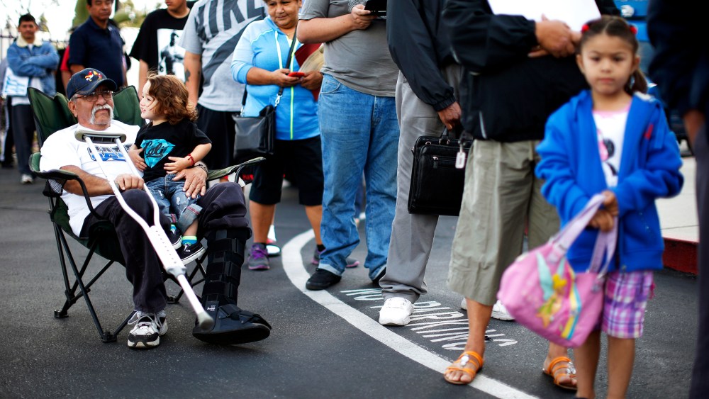 Juan Ortiz, 67, and his eighteen-month-old grandson Joshua Lopez wait in line at a health insurance enrolment event in Commerce, California, Mar. 31, 2014.
