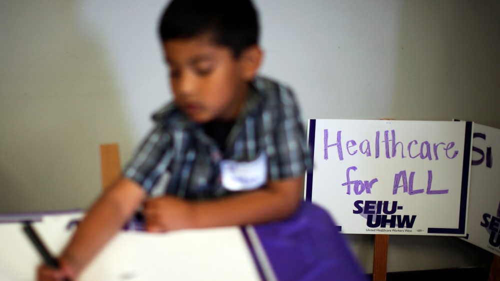 A boy draws signs at a health insurance enrollment event in Commerce, California March 31, 2014.