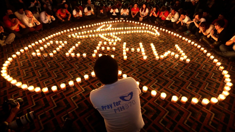 Relatives of passengers onboard Malaysia Airlines Flight MH370 pray during a candlelight vigil in the early morning, in Beijing on April 8, 2014. (Photo by Jason Lee/Reuters)