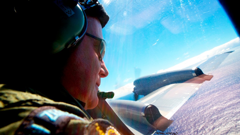 Sergeant Trent Wyatt looks out an observation window aboard a Royal New Zealand Air Force search aircraft as it flies over the southern Indian Ocean looking for debris from missing Malaysian Airlines flight MH370, April 11, 2014.