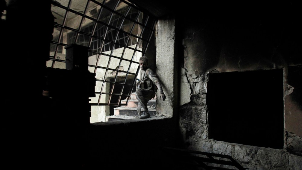 A wounded Islamist rebel fighter carries his weapon during what they said was a takeover of the Furn Al-Ali building that was under control by the Syrian regime in Ramouseh