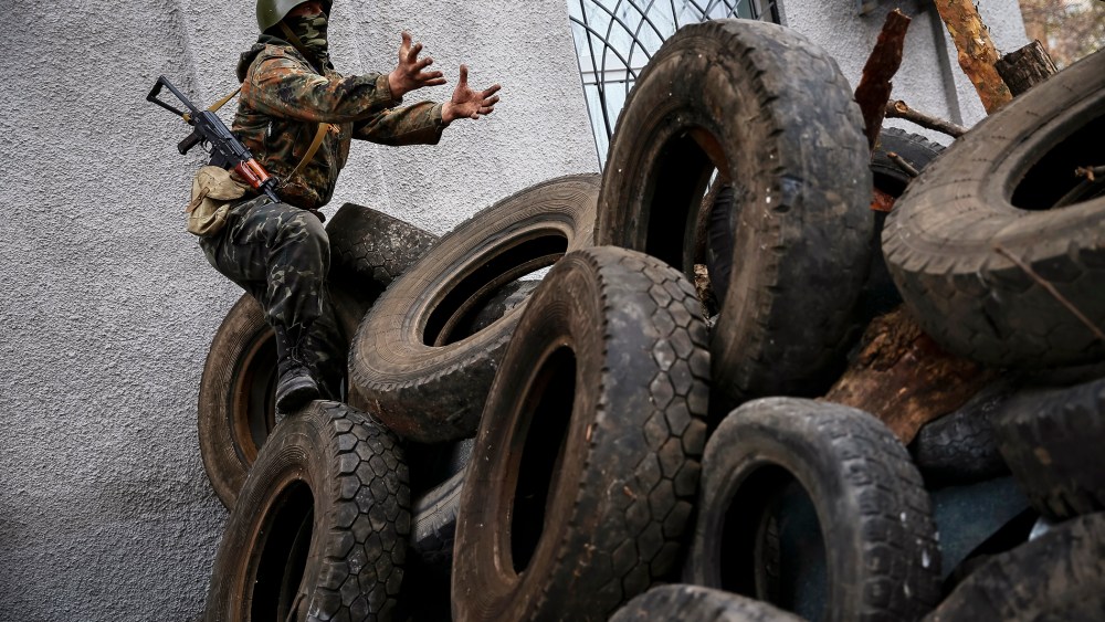 An armed man gestures from a barricade in front of the police headquarters in Slaviansk April 12, 2014.