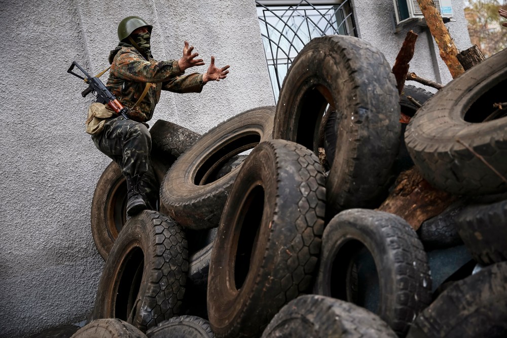 An armed man gestures from a barricade in front of the police headquarters in Slaviansk April 12, 2014.