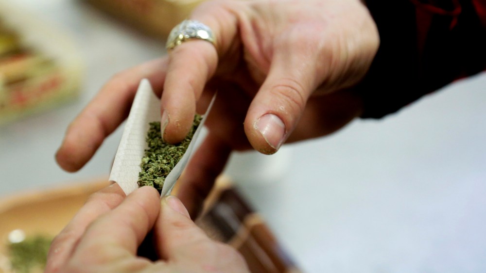 A participant practices rolling a joint. (Photo by Jason Redmond/Reuters)