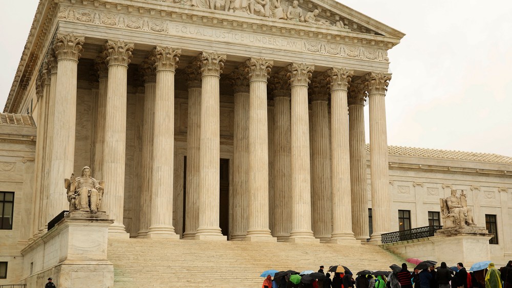 People line up in the rain outside of the U.S. Supreme Court in Washington April 29, 2014.