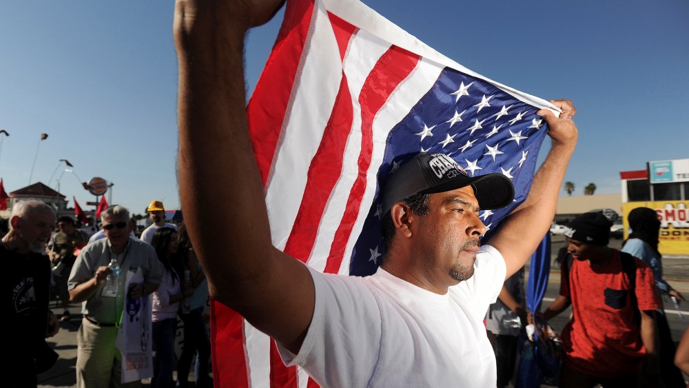 Oscar Rojas carries an American flag during a May Day demonstration in Oakland