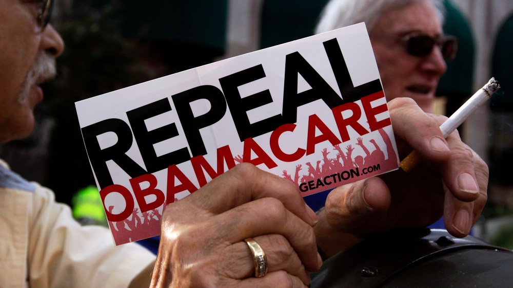 A small group demonstrates prior to former South Carolina Senator Jim DeMint's speech at a "Defund Obamacare Tour" rally in Indianapolis, August 26, 2013.
