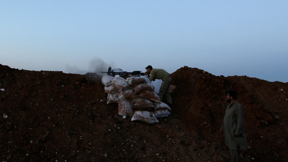 A rebel fighter takes a position as he fires his weapon towards forces loyal to Syria's President Bashar al-Assad who are stationed in Wadi al-Deif military camp in Idlib province June 1, 2014.