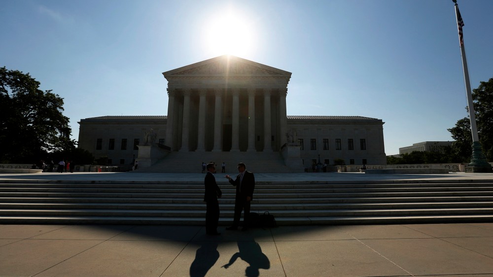 Two men talk as the sun rises over the Supreme Court in Washington, D.C. (Photo by Kevin Lamarque/Reuters)