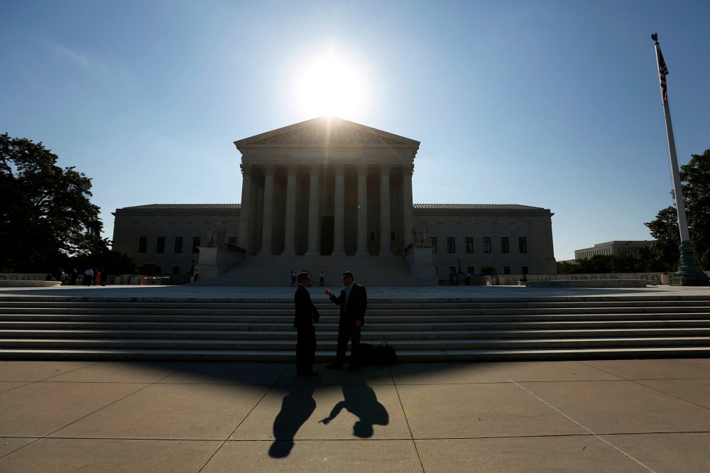 Two men talk as the sun rises over the Supreme Court in Washington, D.C. (Photo by Kevin Lamarque/Reuters)