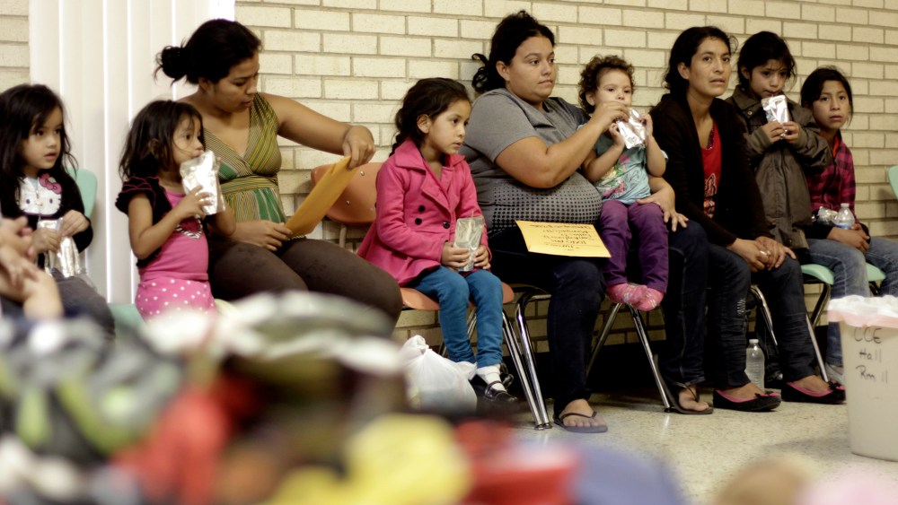 Migrants sit at the Sacred Heart Catholic Church temporary migrant shelter in McAllen, Texas